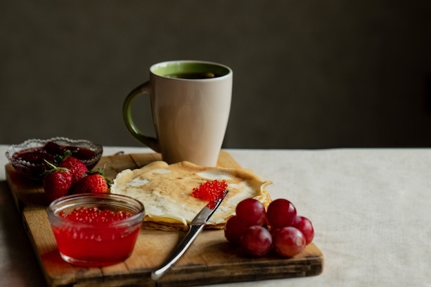 Panqueca com caviar vermelho no café da manhã, uma xícara de chá