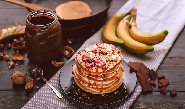 Panqueca com chocolate e pasta de nozes, nozes e banana em um prato preto