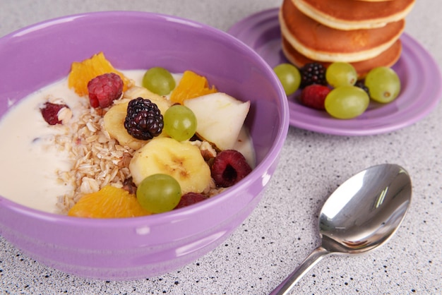 Panqueca com frutas e muesli com leite na mesa de perto