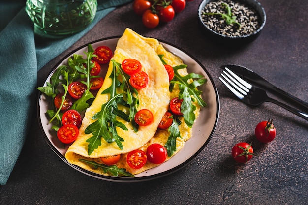 Panqueca de omelete com tomates cereja e rúcula em um prato na mesa