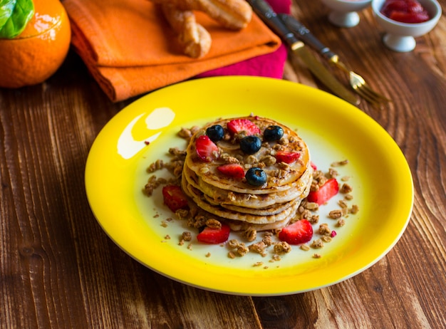 Panquecas caseiras com frutas frescas e calda em uma mesa de madeira