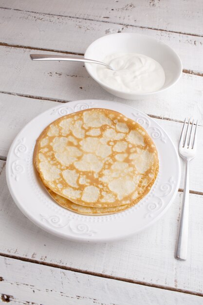 Foto panquecas caseiras panquecas em um prato com creme de leite na mesa de madeira