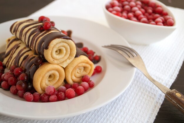 Panquecas caseiras torcidas com chocolate num prato branco.