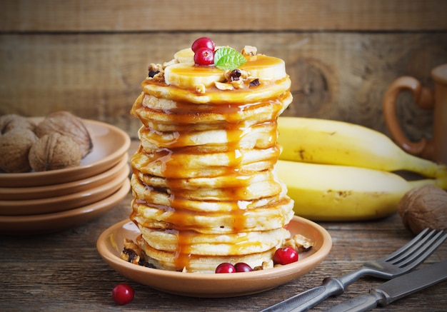 Panquecas com banana, nozes e caramelo no café da manhã.