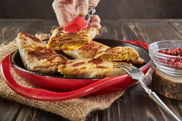 Panquecas com carne com pinças no fundo escuro de madeira.