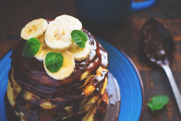 Panquecas com cobertura de chocolate e banana, foco seletivo, tingidas