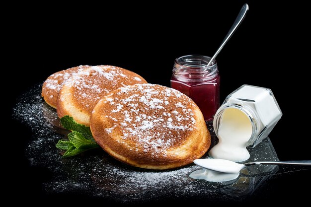 Foto panquecas com creme de leite e framboesa cozinhando em um fundo preto