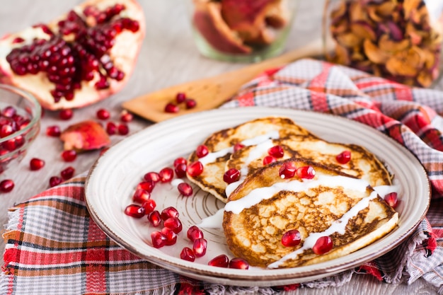 Panquecas com creme de leite e sementes de romã em um prato