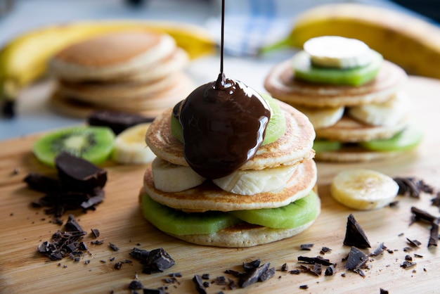 Panquecas com fruta fresca como banana, morango ou kiwi com cobertura de chocolate negro.