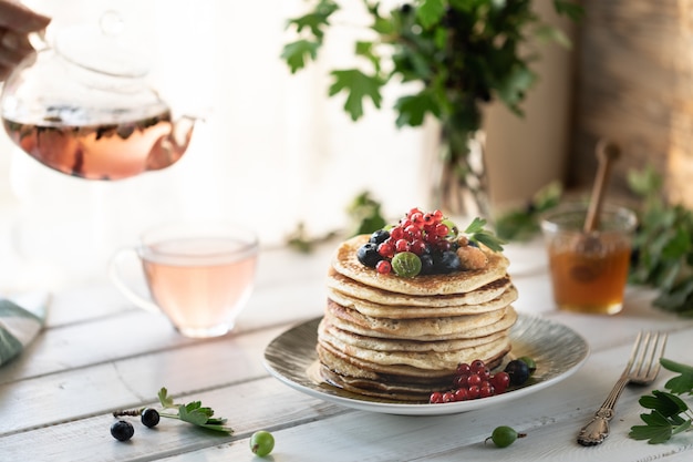 Panquecas com frutas frescas de framboesas, groselhas, mirtilos, com mel e chá