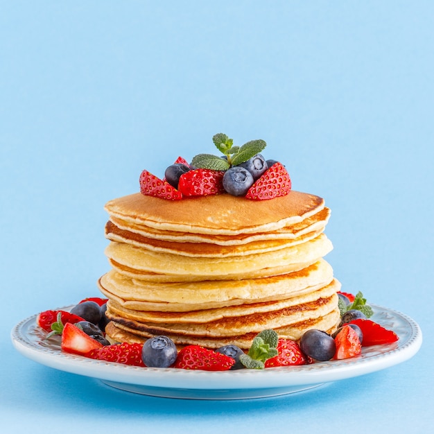 Panquecas com frutas vermelhas em um fundo pastel brilhante