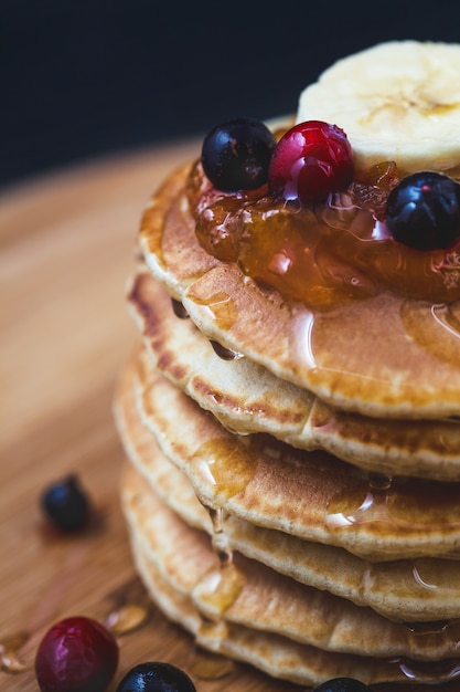 Panquecas com mel, banana, geléia e frutas em uma placa de madeira Menu, receita de restaurante. Servido em