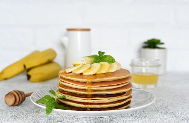 Panquecas com mel e bananas no café da manhã na mesa da cozinha.