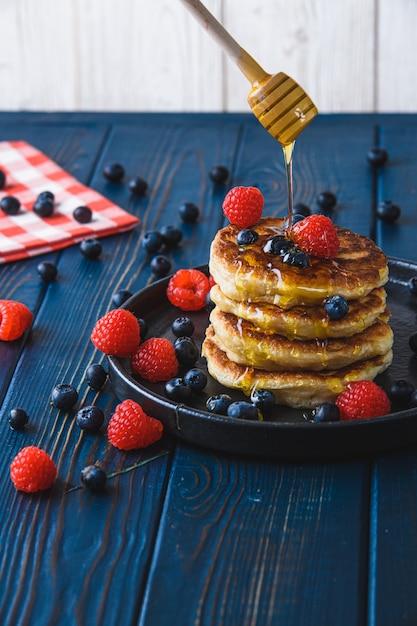 Panquecas com mel e frutas em uma mesa de madeira