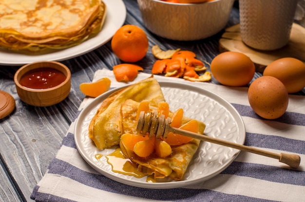 Panquecas com mel e tangerinas em um prato Os ingredientes para fazer panquecas