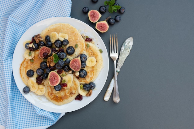 Panquecas com mirtilo, frutos secos e mel. Café da manhã com café e panquecas.