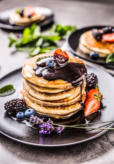 Panquecas com morangos, amoras, mirtilos, levander, folhas de hortelã e chocolate quente.