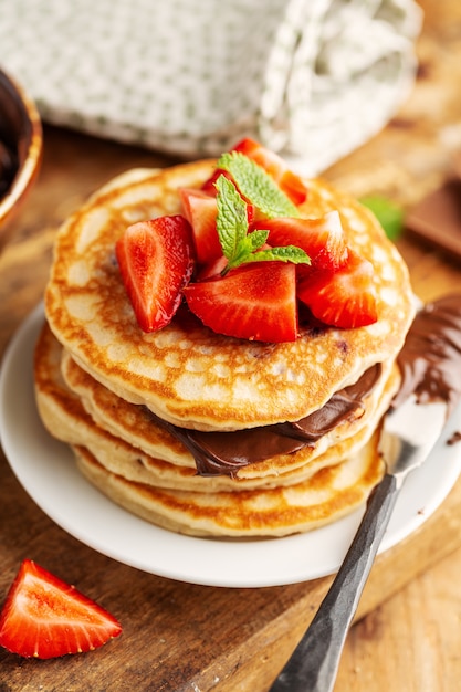 Panquecas de apetitosa saborosa e apetitosa, decoradas com pasta de morango e chocolate servidas no café da manhã. Fechar-se