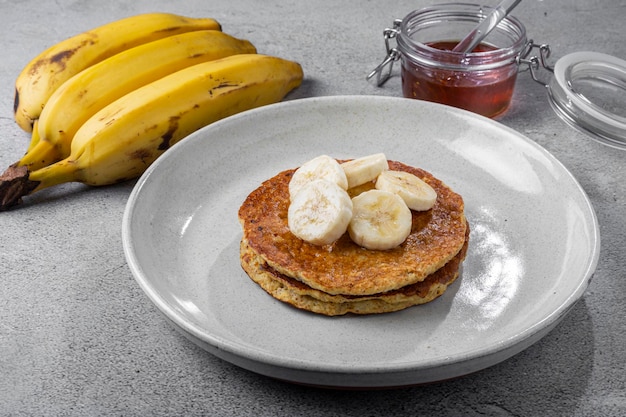 Foto panquecas de aveia e banana cobertas com bananas fatiadas e mel