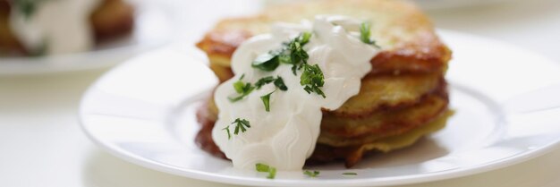 Panquecas de batata com creme de leite e ervas no prato cozinhando o conceito de café da manhã saudável