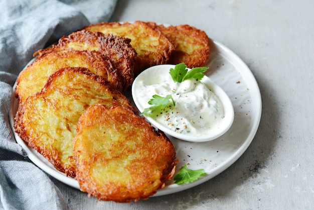 Panquecas de batata crocante com salada verde e molho de iogurte. Pilha de bolinhos de batata