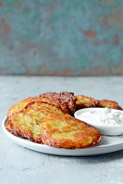 Panquecas de batata crocante com salada verde e molho de iogurte. Pilha de bolinhos de batata