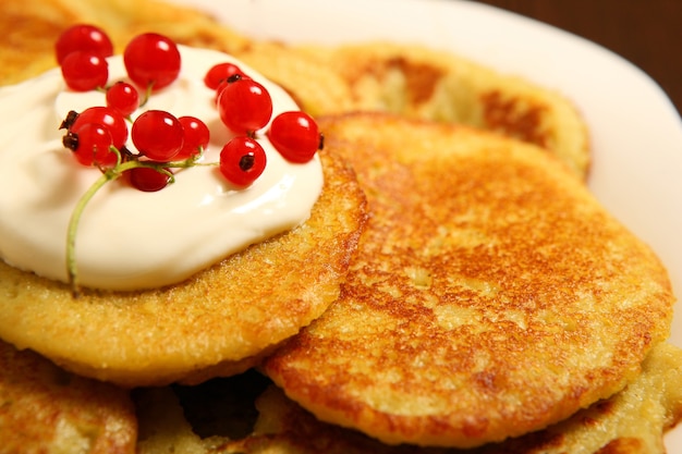 Foto panquecas de batata polonesa tradicionais com creme de leite e groselha vermelha