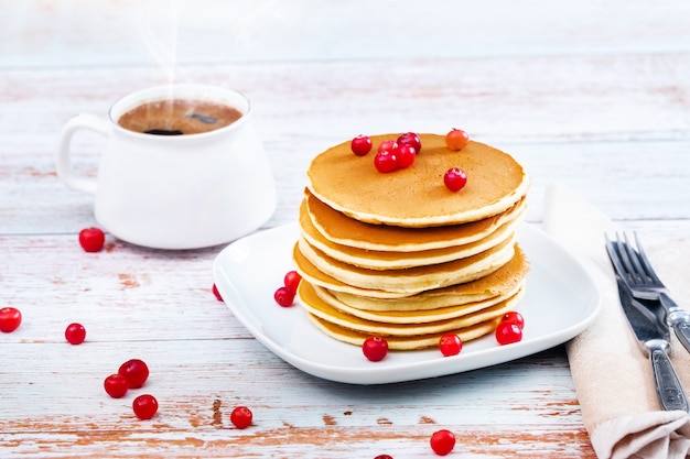 Panquecas de café da manhã com cranberries em uma mesa de madeira e uma xícara de café