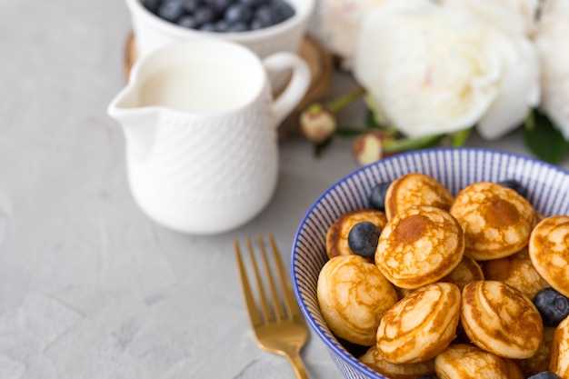 Panquecas de cereal mini com mirtilos em uma tigela na superfície cinza