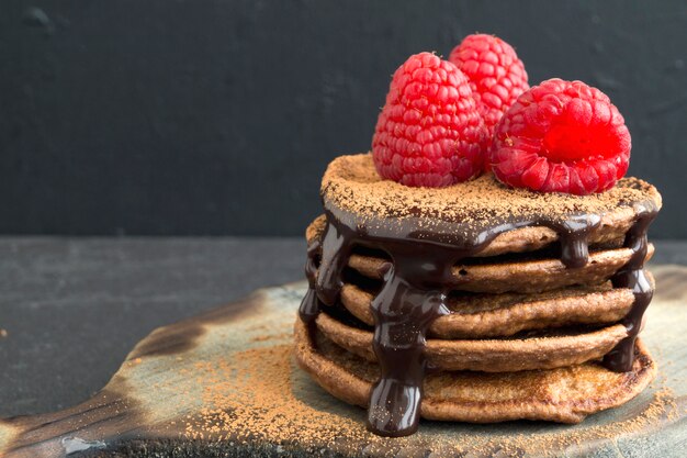 Panquecas de chocolate com framboesa em um fundo escuro.