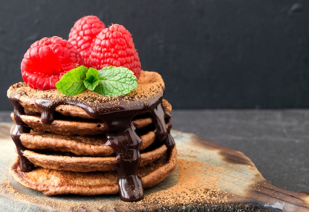 Panquecas de chocolate com framboesa em um fundo escuro.