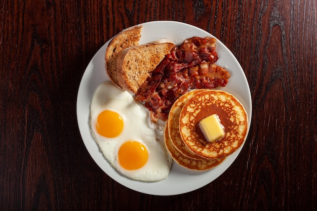 Panquecas de ovos de café da manhã americano completo tradicional com bacon e torradas