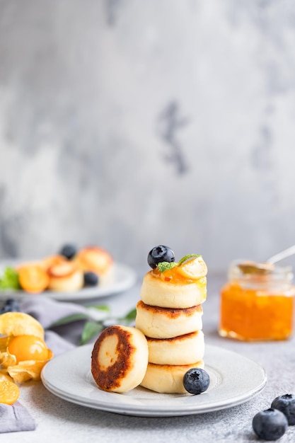 Panquecas de queijo cottage bolinhos de coalhada doce com mirtilo e physalis Syrniki com geléia e frutas