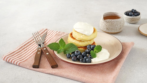 Panquecas de queijo cottage bolinhos de coalhada syrniki com mirtilos frescos e creme azedo no lado do guardanapo