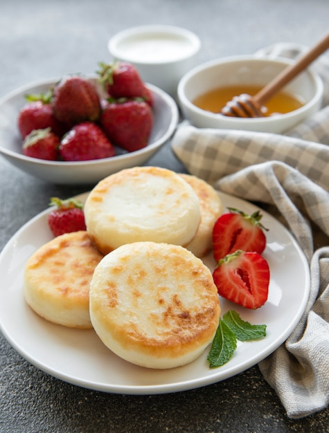 Panquecas de queijo cottage bolinhos de ricota em prato de cerâmica com morango fresco