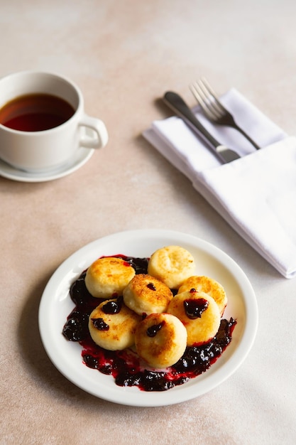 Panquecas de queijo cottage bolinhos de ricota syrniki na placa de cerâmica branca com creme azedo e geléia Café da manhã saudável e delicioso Fundo bege Comida para crianças