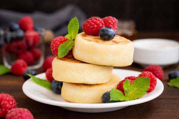 Panquecas de queijo cottage com creme azedo de frutas frescas e mel syrniki ucraniano tradicional