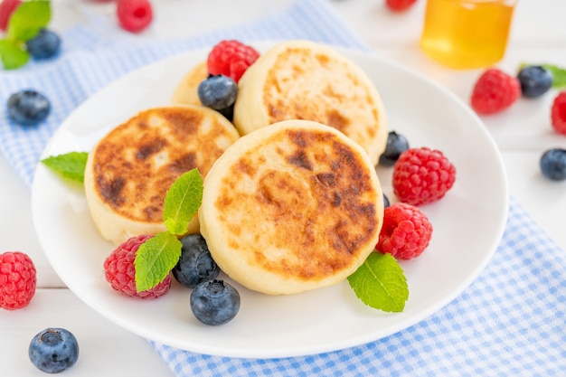 Panquecas de queijo cottage com creme azedo de frutas frescas e mel Syrniki ucraniano tradicional