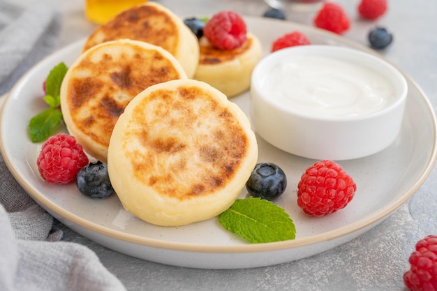 Panquecas de queijo cottage com creme azedo de frutas frescas e mel Syrniki ucraniano tradicional