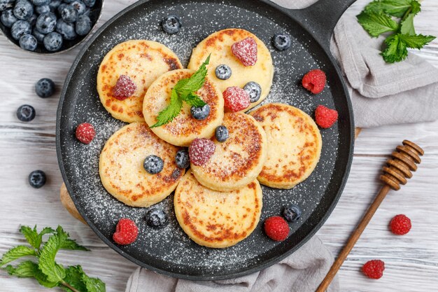 Panquecas de queijo cottage com framboesa e mirtilo em uma panela sobre fundo rústico