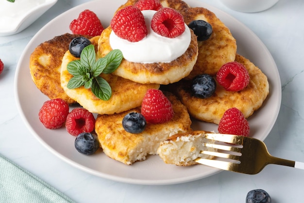 Panquecas de queijo cottage com framboesas e mirtilos no café da manhã ou almoço de fundo claro