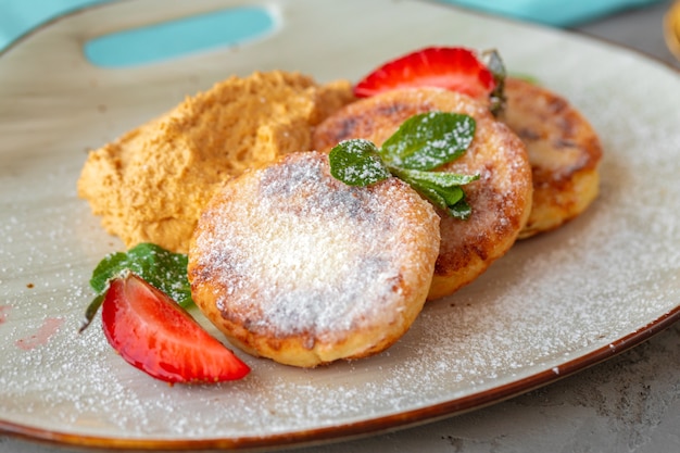 Panquecas de queijo cottage com morango e açúcar em pó