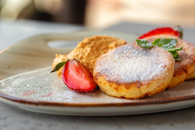 Panquecas de queijo cottage com morango e açúcar em pó