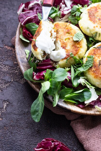 Panquecas de queijo cottage com queijo e ervas, servidas com salada e creme de leite.