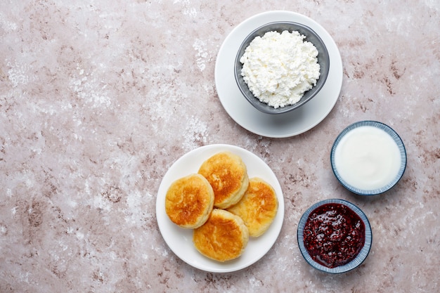 Panquecas de queijo cottage. síria russa ou sirniki, bolinhos de queijo cottage ou panquecas com uma tigela de queijo fresco caseiro