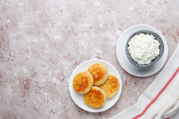 Panquecas de queijo cottage. síria russa ou sirniki, bolinhos de queijo cottage ou panquecas com uma tigela de queijo fresco caseiro