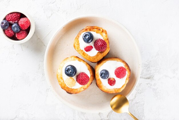 Panquecas de queijo de comida ucraniana tradicional com mirtilos, framboesas e creme azedo