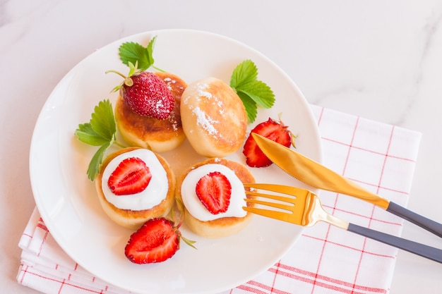 Panquecas de queijo doce no prato servido com morangos. Panquecas de queijo cottage, syrniki, bolinhos de ricota, bolinhos de requeijão. Vista superior ou configuração plana.