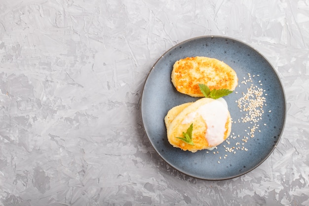 Panquecas de queijo em um prato de cerâmico azul com molho de leite em um concreto cinza.