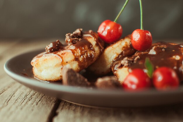 Panquecas de requeijão com cereja e chocolate em um prato marrom